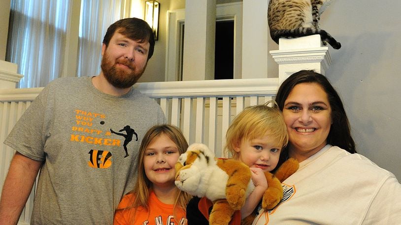 The Young family of Piqua: from left, Brandon, Lily, 9; Ivy, 2; and Melissa, are lifelong Bengal fans. MARSHALL GORBY/STAFF