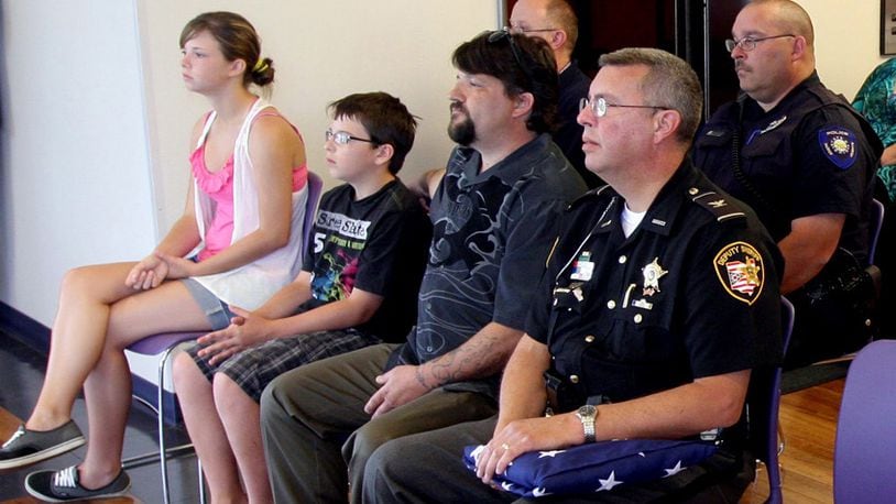 Matthew Hopper, the husband of fallen Clark County Deputy Suzanne Hopper, and his children, Madeline and Cole Hopper, sit in the front row with Clark County Chief Deputy David Rapp during the dedication of a new firearms training simulator (FATS) in Suzanne Hopper's memory at the Dayton campus of Kaplan College Saturday, June 11, 2011. E.L. Hubbard photography