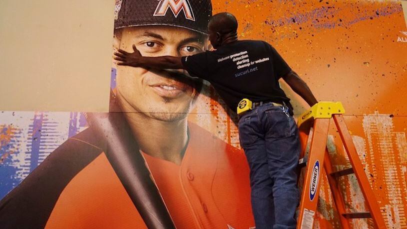 Francois Diesiul hangs a poster bearing the visage of Marlins star Giancarlo Stanton, Thursday, July 7, 2017, at the Miami Beach Convention Center where the Major Leaqgue All Star Game FanFest will open Friday morning...SOUTH FLORIDA OUT; NO MAGS; NO SALES; NO INTERNET; NO TV...