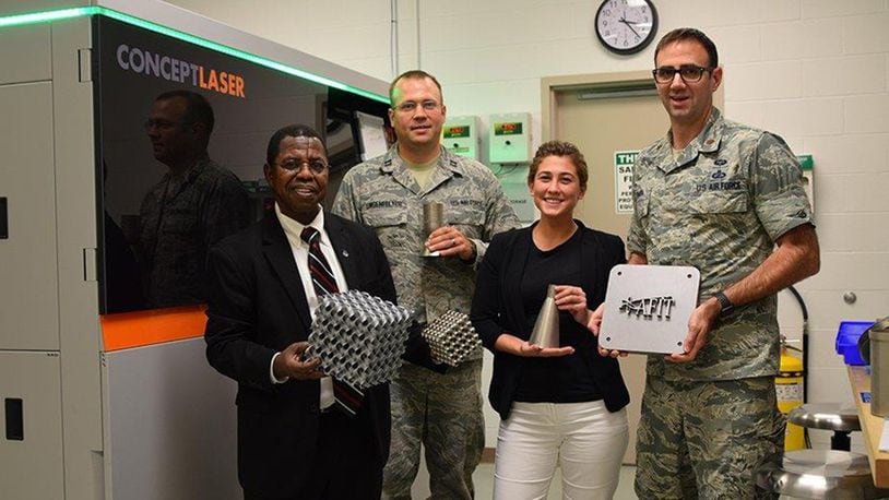 Dr. Adedeji Badiru, Capt. Andrew Lingenfelter, Jessica Smith and Maj. Ryan O’Hara stand with samples made from Air Force Institute of Technology’s state-of-the-art metal additive manufacturing system. (U.S. Air Force photo/Katie Scott)