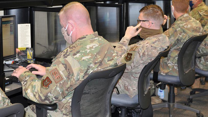 Master Sgt. Kevin Kelly(left) , Staff Sgt. Mitchiner Underhill and other members of the 445th Security Forces Squadron work to complete required readiness training in the SFS computer lab, despite new challenges associated with the COVID-19 pandemic. To protect themselves and others, members of the squadron wore masks and sanitized high-touch areas throughout the day, in addition to sanitizing communal work stations, like these, before and after each use. (U.S. Air Force photo/1st Lt. Rachel Ingram).