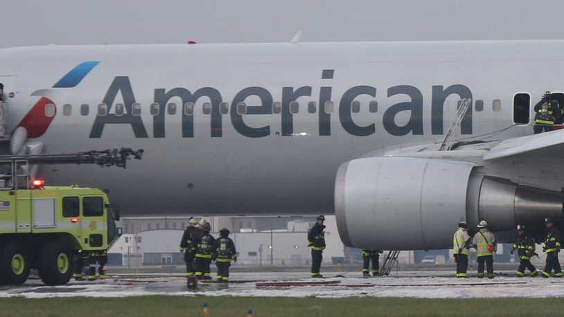 A fire-damaged American Airlines jet is checked over by Chicago firefighters following a blaze on the jet at O&apos;Hare International Airport in Chicago on Friday, Oct. 28, 2016. (Antonio Perez/Chicago Tribune/TNS)