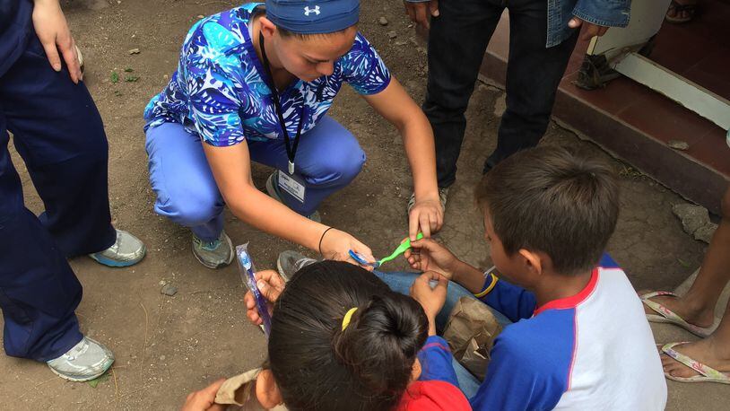 University of Dayton soccer player Sarah Byrne working on a medical brigade with two small Nicaraguan kids on personal and dental hygiene. CONTRIBUTED
