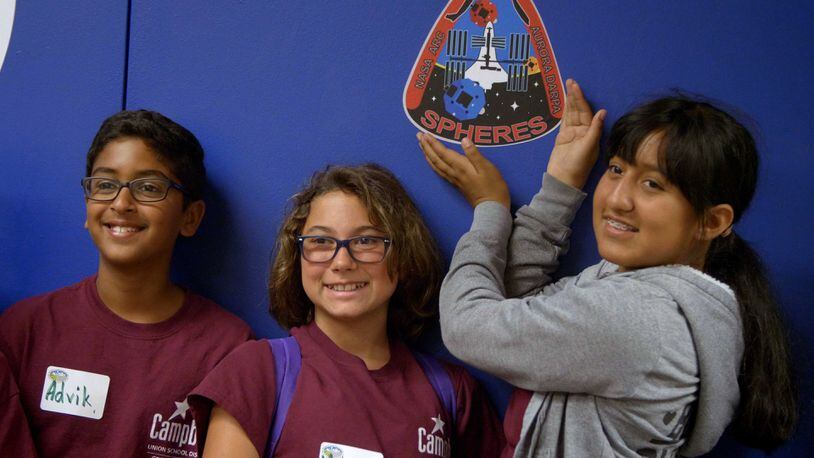 left to right: Advik Gonugunta, Adrien Engelder, and Carol Gonzalez pose in front of the SPHERES mission
patch at NASA AMES Research Facility during the Zero Robotics ISS Finals Tournament. CONTRIBUTED