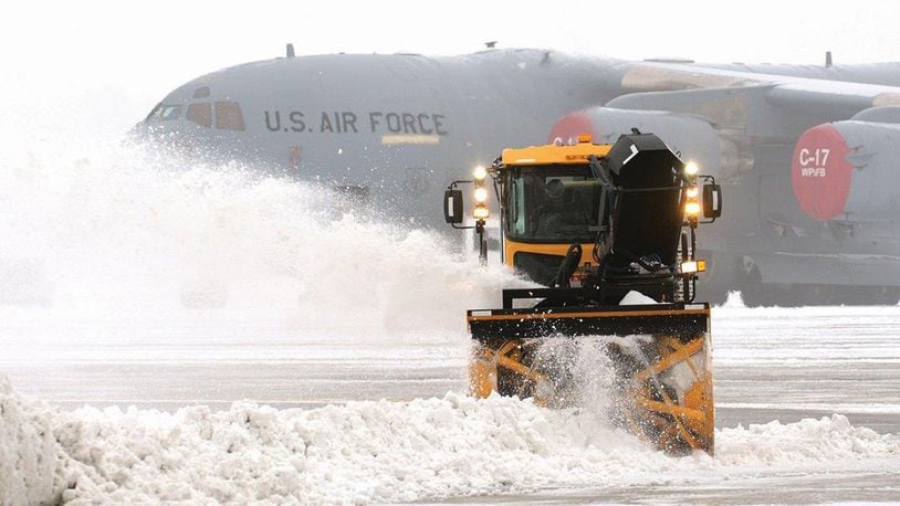Snow surrounding a 445th Airlift Wing C-17 Globemaster III sitting on the ramp is removed as temperatures drop and fog rolls in during a 2014 winter storm at Wright Patterson Air Force Base. With the return of winter weather, officials have announced procedures for Base-wide early release, delayed reporting and base closure due to hazardous weather-related events. (U.S. Air Force photo/Tech. Sgt. Frank Oliver)