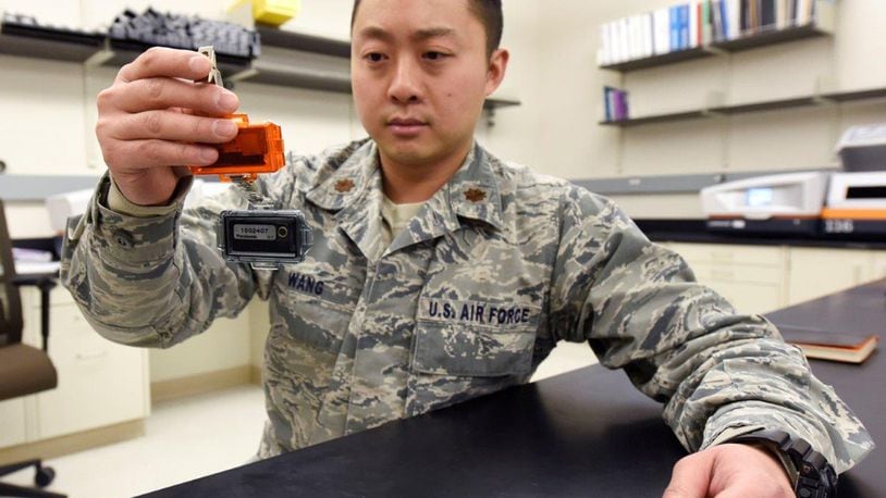Maj. John Wang, health physicist, United States Air Force School of Aerospace Medicine Radiation Dosimetry Lab inspects a dual radiation dosimeter at Wright-Patterson Air Force Base Dec. 19, 2019. For the first time in nearly 40 years, U.S. Air Force personnel who work near radioactive materials will be receiving newly designed, higher-sensitivity radiation dosimeters designed and fielded by USAFSAM Radiation Dosimetry Lab. The dosimeters record the amount of exposure to ionizing radiation for individuals. U.S. AIR FORCE PHOTO/TY GREENLEES