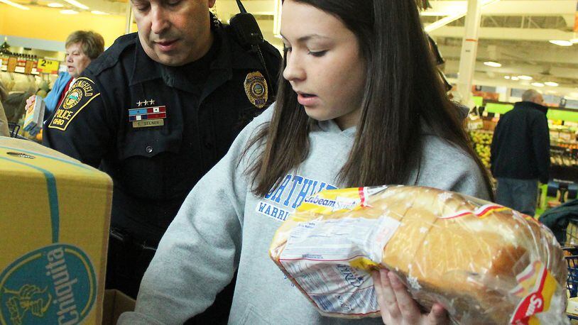 Springfield Police Division officer, Tom Selner helps Jillian Tedeschi pack a box of food for those less fortunate on Thanksgiving. JEFF GUERINI/STAFF