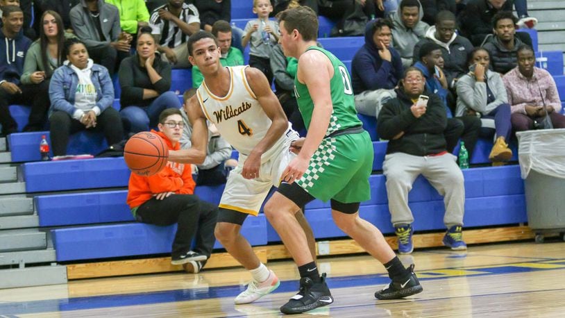 Springfield High School senior David Sanford passes the ball to a teammate against Northmont defender Miles Johnson during the Wildcats’ 78-64 victory over the Thunderbolts on Friday night in Springfield. Sanford had a team-high 21 points in the win. CONTRIBUTED PHOTO BY MICHAEL COOPER