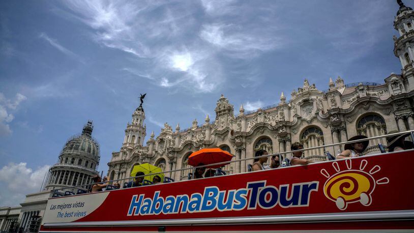 FILE - In this June 17, 2017 file photo, a tour bus appears in front of the Capitolio in Havana, Cuba..Tour companies and others in the travel industry say they will continue taking Americans to Cuba despite a dramatic safety warning issued Friday by the U.S. State Department. (AP Photo/Ramon Espinosa, File)