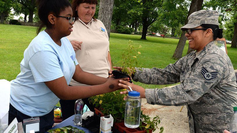 Raejean Smith, Five River Metro Parks volunteer, gives a Lantana plant to Staff Sgt. Cassandra Mena, United States Air Force School of Aerospace Medicine industrial hygiene laboratory technician, during the Pollinator Expo held at the Wright Brothers Memorial located outside Wright-Patterson Air Force Base June 21. Numerous local organizations were on site to highlight the work they do to protect pollinators and their habitats. (U.S. Air Force photo/Michelle Gigante)