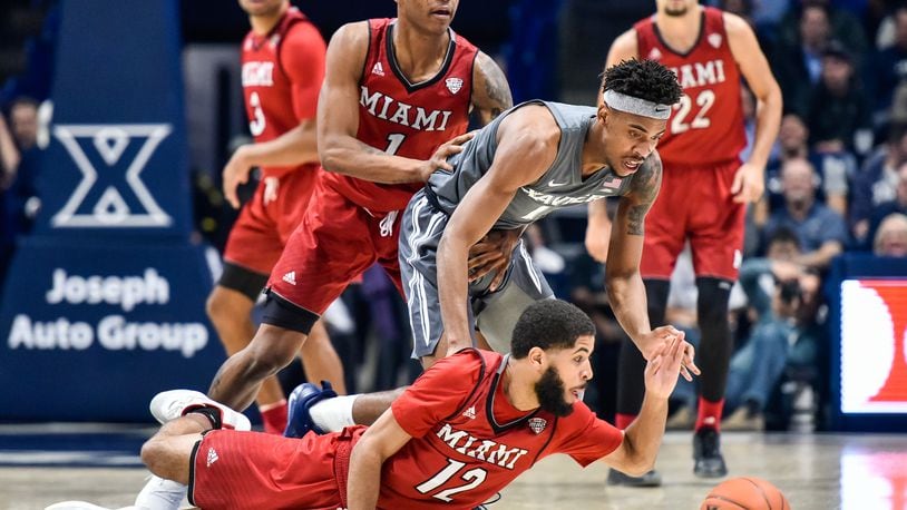Miami’s Darrian Ringo (12) and Xavier’s Paul Scruggs (1) battle for the ball on the ground during their basketball game Wednesday, Nov. 28, 2018, at Xavier’s Cintas Center in Cincinnati. NICK GRAHAM/STAFF