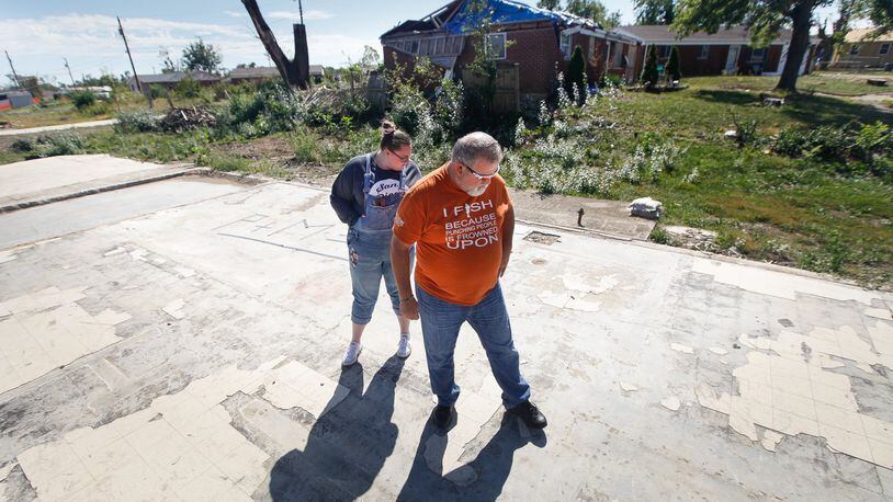 Ed Kirklin and his daughter Kenzie Banta walk over the slab foundation where their house once sat on Crosswell Avenue in Brookville. Kirklin decided to move the family to Englewood and plans not to rebuild. CHRIS STEWART / STAFF