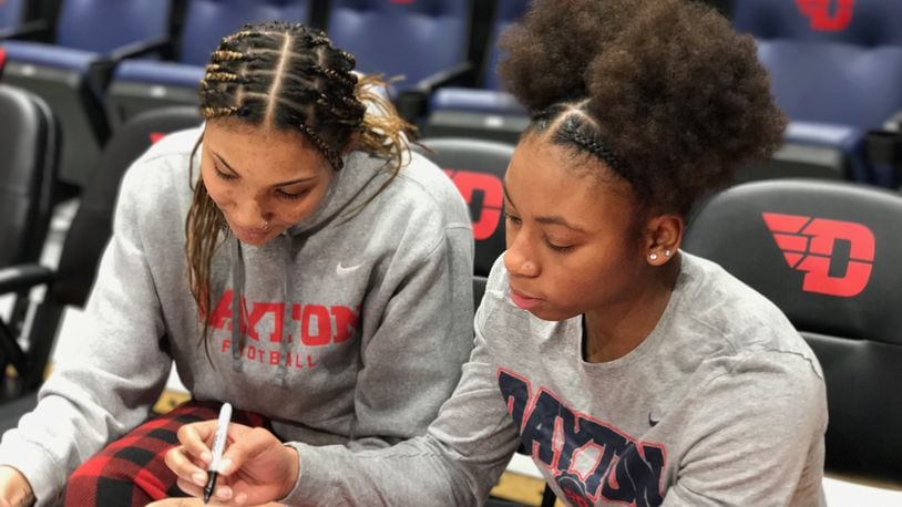 Univeristy of Dayton women's basketball players Eve Fiala (left) and Denika Lightbourne sign autographs after Sunday's game at UD Arena. Tom Archdeacon/CONTRIBUTED
