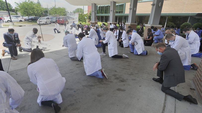 Grandview Medical Center staff kneel in their white coats Friday as part of White Coats for Black Lives. They joined healthcare professionals across the county in a moment of silent reflection and commitment to improve the health and safety of peopleof color. MARSHALL GORBYSTAFF
