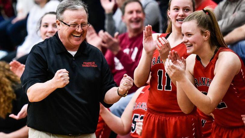 Franklin coach John Rossi starts to enjoy his team’s Division II sectional championship with Kristin Earles (11) and Madison Earles (22) late in the Feb. 26 game against Monroe at Lebanon. NICK GRAHAM/STAFF