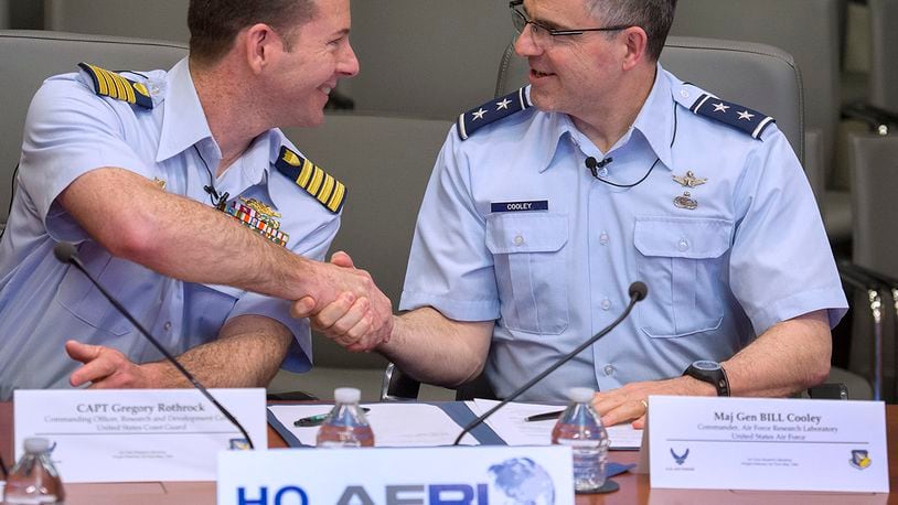 Coast Guard Capt. Greg Rothrock, left, commander of the Coast Guard Research and Development Center, and Maj. Gen. William Cooley, former commander of Air Force Research Lab, shake hands in April 2018 at Wright-Patterson Air Force Base after they signed a memorandum of understanding between their two organizations. (U.S. Air Force photo by R.J. Oriez)