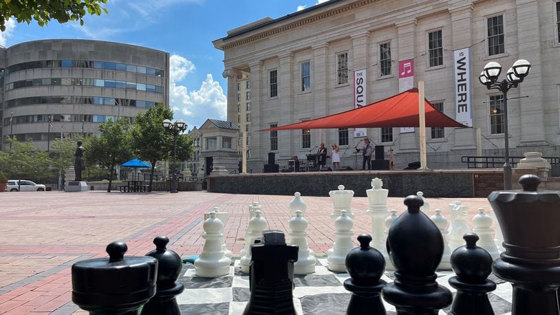 A band performs at lunchtime on Friday on the stage at Courthouse Square as part of the "Square is Where" program. An oversized chess board is one of the games people can play. CORNELIUS FROLIK / STAFF