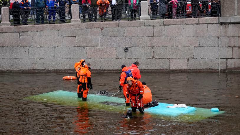 Emergency responders work to recover victims of a bus crash in St. Petersburg, Russia, Friday, May 10, 2024. Authorities in St. Petersburg say that at least one person died and five others were hospitalized with injuries when a bus fell off a bridge in St. Petersburg. (AP Photo/Dmitri Lovetsky)
