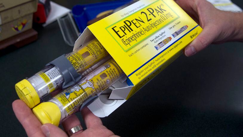 FILE - In this July 8, 2016, file photo, a pharmacist holds a package of EpiPens epinephrine auto-injector, a Mylan product, in Sacramento, Calif. Mylan has started selling a generic version of its emergency allergy treatment EpiPen at half the price of the branded option, the cost of which drew national scorn and attracted Congressional inquiries. (AP Photo/Rich Pedroncelli, File)