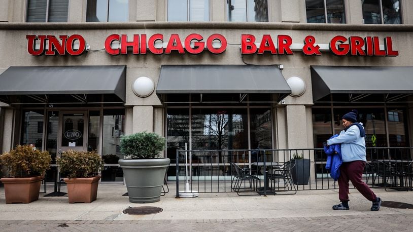 A pedestrian walks by Uno Chicago Bar & Grill Friday March 1, 2024. A sign on the door stated the pizzeria closed to the public February 29. JIM NOELKER/STAFF