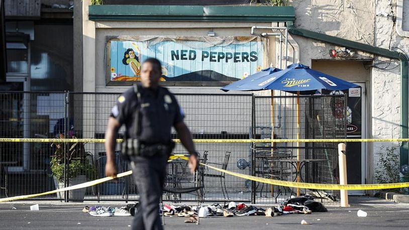 A Dayton officer walks near Ned Peppers the morning after nine people were shot and dozens injured in the Aug. 4 Oregon District mass shooting.