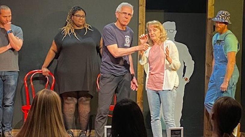 Dean Waggenspack pretends to hold a micophone up to his wife Rose Waggenspack  as they take center stage during a Black Box Improv Theater show. CONTRIBUTED