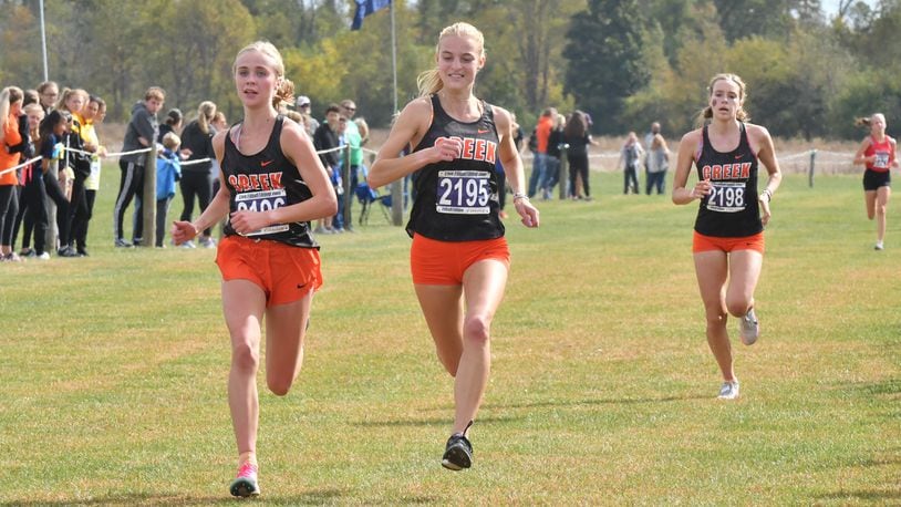 Beavercreek’s Savannah Roark (left), Jodie Pierce (middle) and Juliann Williams (right) attempt to help the Beavers defend their Division I state cross country title Saturday. Greg Billing / Contributed