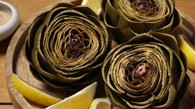 Artichokes steam in a lemon-, garlic- and bay leaf-scented bath until tender. A tahini dip for dunking brings more lemon and garlic to the dish. (E. Jason Wambsgans/Chicago Tribune/TNS)