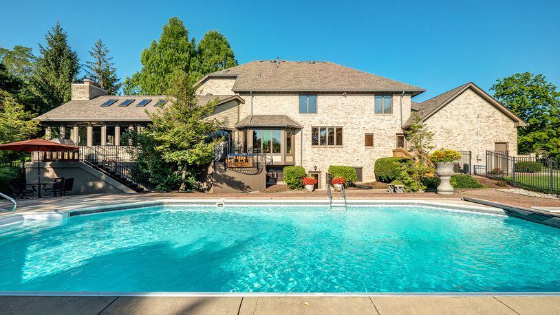 Recreational amenities abound at the back of the home with an in-ground swimming pool with a paver walk-around, a partially enclosed fire pit with built-in seating and a lighted tennis court with a side viewing area installed with wood bleachers.