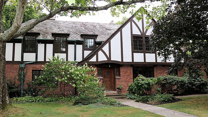 The 4-bedroom Tudor-style home has about 3,590 sq. ft. of living space, plus a finished basement.  Leaded-glass windows flank the carved wood door, and a slate roof peaks above the brick-and-stucco exterior. CONTRIBUTED PHOTO BY KATHY TYLER
