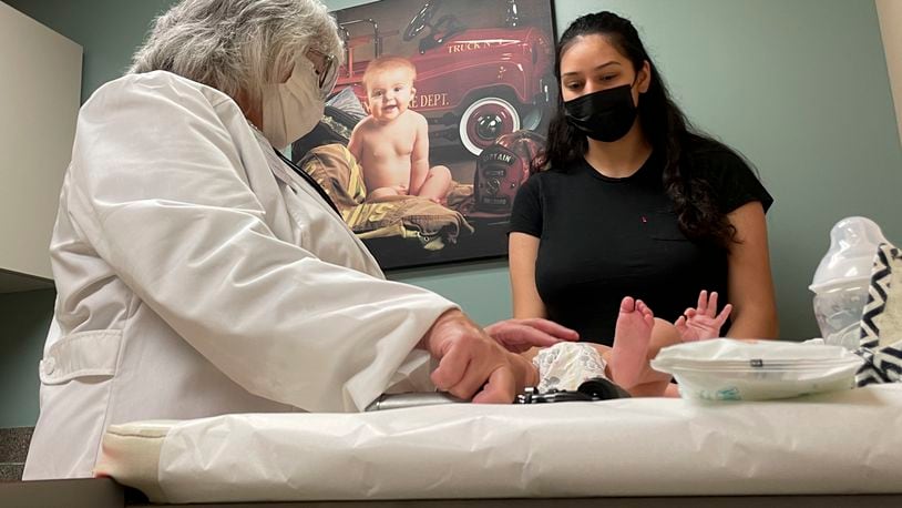 File - Dr. Sara Goza explains an infant's upcoming vaccinations to his mother in an exam room at First Georgia Physician Group Pediatrics in Fayetteville, Ga., Tuesday, Aug. 17, 2021. (AP Photo/Angie Wang)