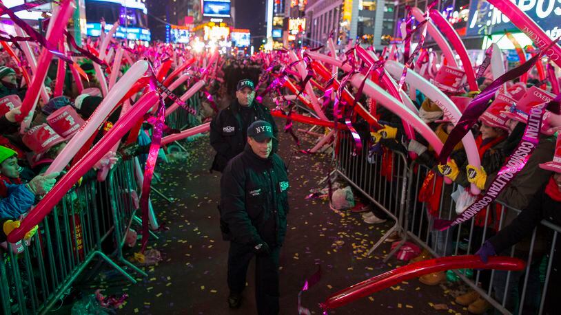 New York City police officers walk past revelers as they wait in Times Square for the stroke of midnight during New Year's Eve festivities in New York, Wednesday, Dec. 31, 2014. (AP Photo/Craig Ruttle)