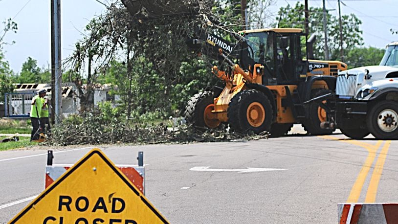 Public works workers continue to clean up tornado debris on Benchwood Road in Butler Twp. where a car reportedly hit a worker after crashing though the road closed sign. (Marshall Gorby/Staff)