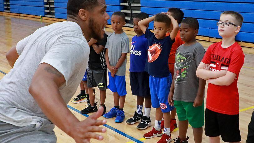 Nate Miller, a Springfield South graduate and professional basketball player, talks to some young players about defense Thursday during the Springfield Youth Basketball Camp at Springfield High School. BILL LACKEY/STAFF