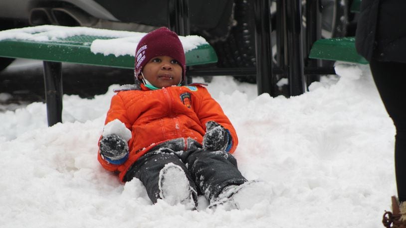 A boy plays in the snow during a voter rights rally in Dayton, which followed the MLK Memorial March on Monday. CORNELIUS FROLIK / STAFF