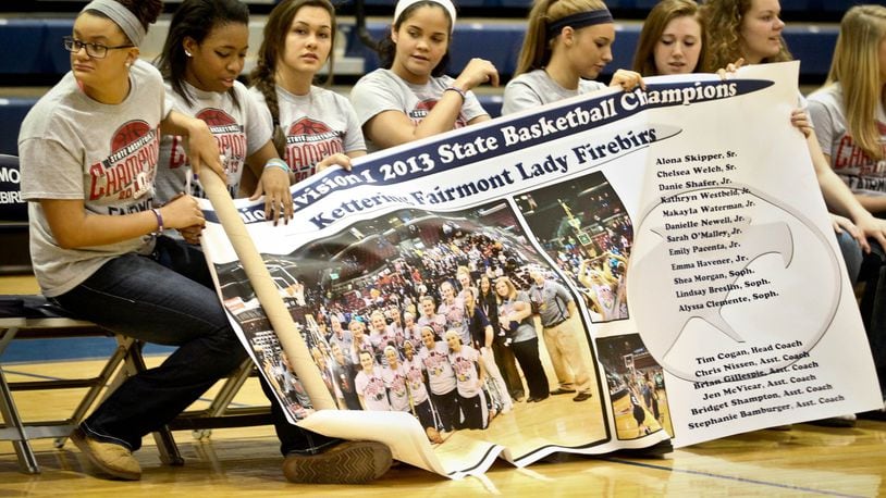 Members of the Fairmont High School girls basketball team unfurl a banner commemorating their Division I state title. The Firebirds were honored at Trent Arena on Tuesday with a ceremony attended by student, staff and local dignitaries. Fairmont completed a 27-1 season by defeating Twinsburg 52-48 in the title games. Twinsburg beat Fairmont in the previous two state title games. By JIM WITMER / STAFF