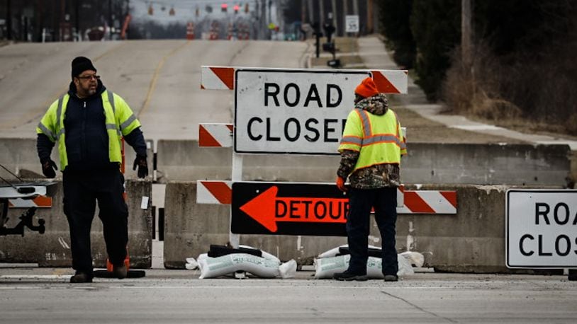 Workers set more sandbags on the road closed signs at Ohio 49 and East Main Street Friday, Feb. 10, 2023. The bridge over Dry Run is going to be repaired because of erosion. JIM NOELKER/STAFF