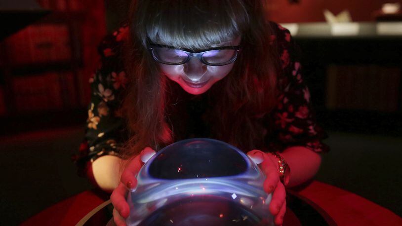 A member of British Library staff poses with a crystal ball for a picture at the "Harry Potter - A History of Magic" exhibition at the British Library, in London, Wednesday Oct. 18, 2017.  The exhibition running from Oct. 20, marks the 20th anniversary of the publication of Harry Potter and the Philosopher's Stone, showing items from the British Library's collection, and items from author J.K Rowling and the book publisher's collection. (AP Photo/Tim Ireland)
