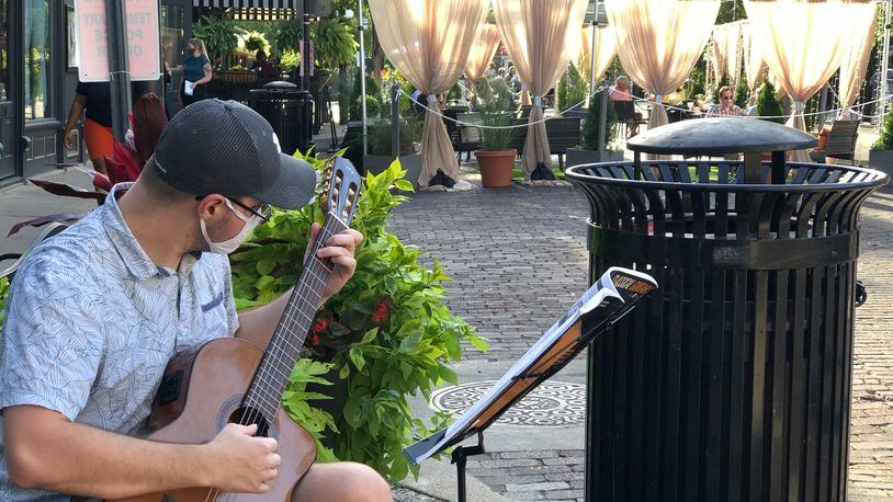 A musician plays a guitar near Salar's outdoor patio during Out on 5th. Salar expanded its seating during the program, which shut down the street on weekends. CORNELIUS FROLIK / STAFF