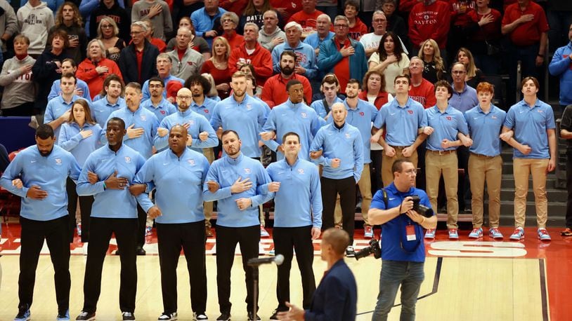 Dayton coaches and staff members stand for the national anthem before a game against St. Bonaventure on Friday, Feb. 2, 2024, at UD Arena. David Jablonski/Staff