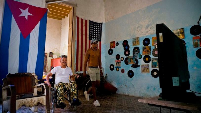 A U.S. and a Cuban flag hang from the wall of the home of Armando Ricart, a former boxer, carpenter and actor while he watches President Donald Trump's inauguration speech on television, in Havana, Cuba, Friday, Jan. 20, 2017. Donald Trump became the 45th president of the United States Friday, Jan. 20 2017, amid apprehension in Cuba regarding his campaign remarks on U.S. - Cuba relations. (AP Photo/Ramon Espinosa)