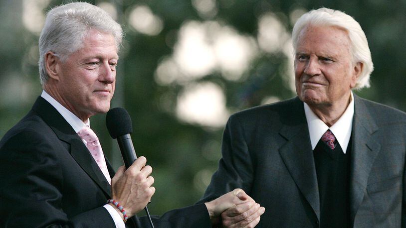 Former U.S. President Bill Clinton holds Billy Graham's hand as he speaks during Graham's Crusade at Flushing Meadows Corona Park June 25, 2005 in the Queens borough of New York. (Photo by Stephen Chernin/Getty Images)
