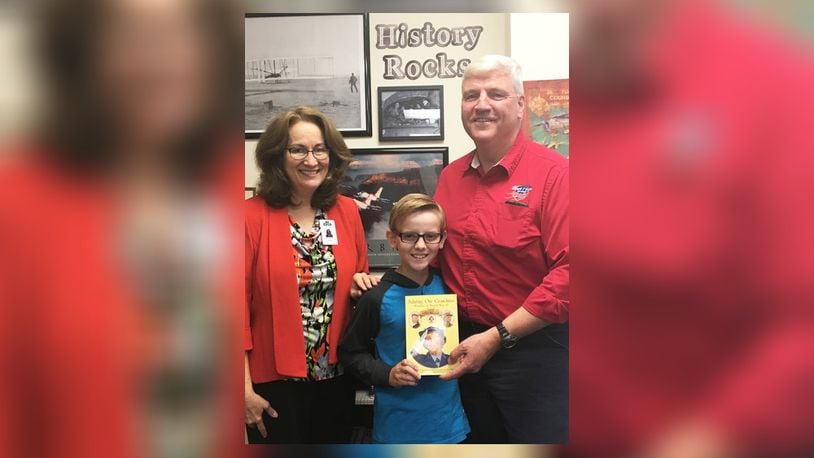 East Dayton Christian School history teacher Sue Norrod, student EZ Morse and his grandfather and founder of Honor Flight, Earl Morse, on Oct. 7 with the book that surprised EZ and brought “Pappy” to his school. CONTRIBUTED