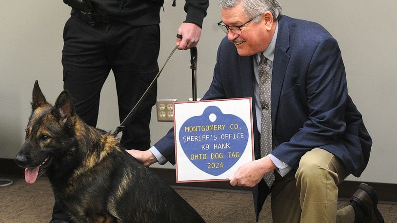 Montgomery County Auditor Karl Keith pets Montgomery County Sheriff's K9 Hank, after presenting his handler a undercover deputy his Ohio dog tag Thursday, Jan. 18, 2024. MARSHALL GORBY\STAFF