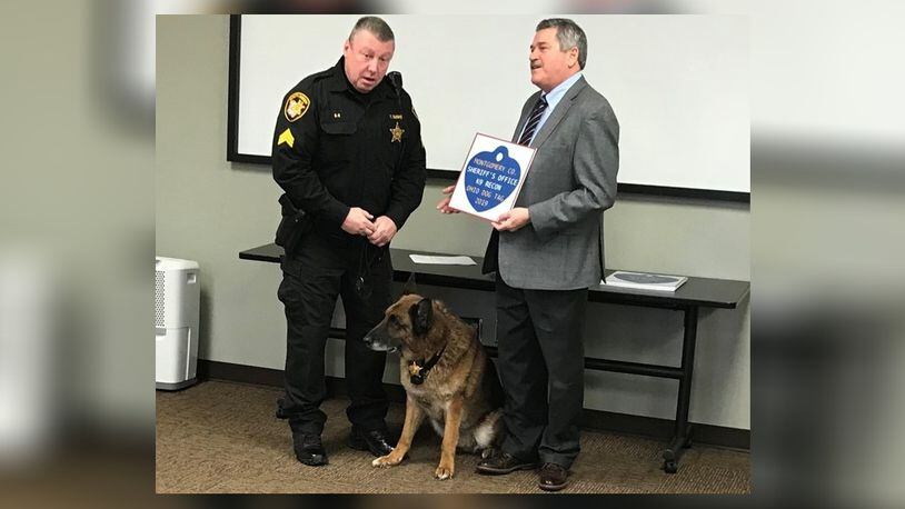 Montgomery County Auditor Karl Keith, right, presents a 2019 dog license to K-9 Recon and his handler, deputy Troy Bodine.