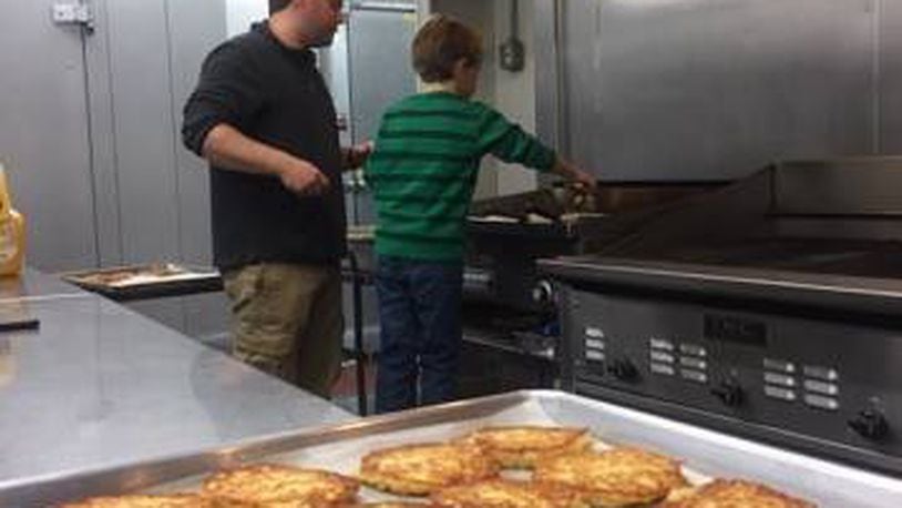 Adam Baumgarten of Bernstein's Fine Catering makes cooking latkes a family affair with the help of his son. (CONTRIBUTED)