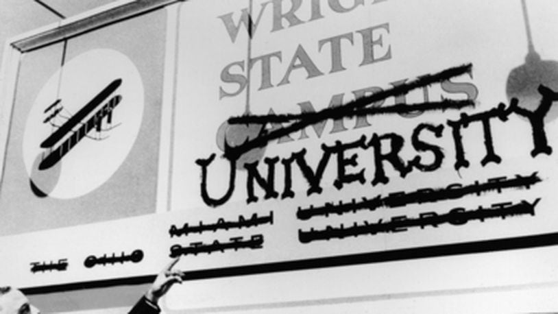 Wright State’s first president, Brage Golding, points at a sign with Miami University and Ohio State University crossed off at the bottom.