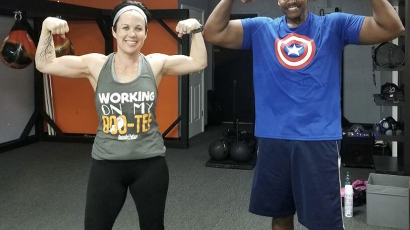 Retired Master Sgt. and financial management specialist Daryl McFadden, flexes with one of his fitness partners, Christina Millard, after a workout. McFadden, who has survived cancer twice and undergone a triple bypass surgery, makes his health his priority by continuing to exercise and changing his eating habits. (Courtesy photo)
