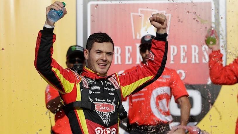 Kyle Larson raises his arms after exiting his car after winning a NASCAR Sprint Cup series auto race, Sunday, June 18, 2017, in Brooklyn, Mich. (AP Photo/Carlos Osorio)