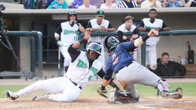 Phillip Ervin of the Dragons (left) avoids the tag of catcher Michael Quesada, but also missed home plate and was tagged out against the Cedar Rapids Kernels (Twins) at Dayton’s Fifth Third Field on Monday, July 28, 2014. MARC PENDLETON / STAFF